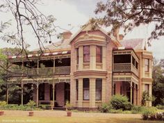 an old house with lots of windows and balconies on the second floor is surrounded by greenery