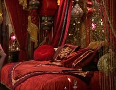 a woman sitting on a bed in a room with red drapes and decorations around her