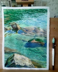 a watercolor painting of rocks in the middle of a lake with green and blue colors