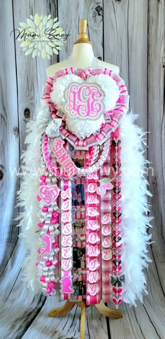 a mannequin with pink and white feathers on it's head, wearing a monogrammed top