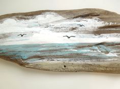 a piece of wood with birds flying over the water and clouds in the sky on it