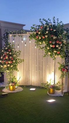 an outdoor wedding setup with flowers and greenery on the grass, surrounded by lights