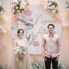 a man and woman standing in front of a floral display