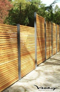 a wooden fence with metal posts on the top and bottom part, along side it