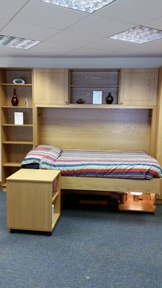 a bed sitting in the middle of a room next to a book shelf and desk