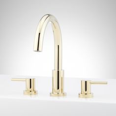 two gold faucets on a white counter top