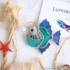 a brooch with a fish and starfish on it next to some sea shells