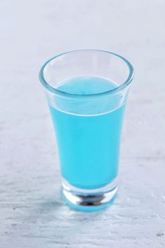 a glass filled with blue liquid sitting on top of a table