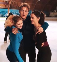 three people are hugging on an ice rink