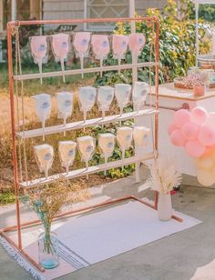 a table topped with lots of pink and white glasses on top of a metal rack