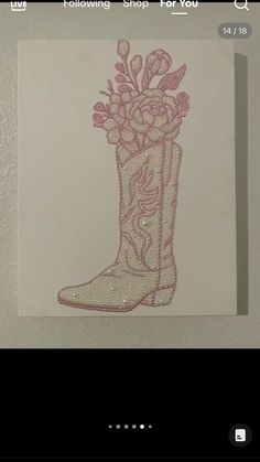 a drawing of a boot with flowers in it on a white paper sheet that is hanging from the wall