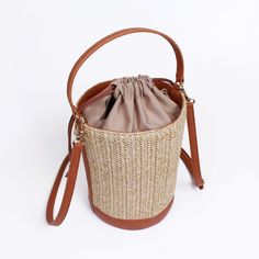 Made from high quality Raffia. Vegan leather trim. Polyester lining. Our raffia line are all made with an interior liner to keep your items safe and enclosed from beach sand or any harsh environment. Great size for traveling and for the summer heat.  Detachable shoulder strap included. Dimensions: 150x215X150mm Weight:  286g (bag) SHIPPING:  Free shipping from South Korea, estimated 7-14 days to get to you from purchase date.  RETURNS:  Return address is in USA so that returns can be made and given fast.  Returns up to 2 weeks starting when the shipping is completed.  Returns must be with tags.  Buyer must pay for return shipping unless item was damaged or incorrect.  Money will be refunded after we receive and inspect the item. Orders over $250 will have to pay 20% restocking fee. Daily Use Straw Bucket Bag With Adjustable Strap, Straw Bucket Bag For Travel, Straw Travel Bucket Bag, Vacation Bucket Shaped Shoulder Bag With Leather Handles, Vacation Bucket Shoulder Bag With Leather Handles, Chic Brown Bucket Bag For Beach Season, Beige Woven Bucket Shoulder Bag, Chic Straw Bucket Bag For Travel, Chic Bucket Straw Bag For Travel