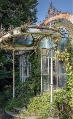 an old gazebo with vines growing on it's sides in the middle of a garden