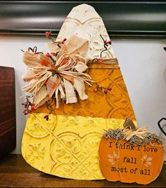 a wooden pumpkin sitting on top of a table next to a sign that says i think i love fall most of all