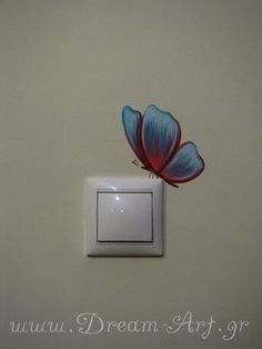 a white light switch with a blue and red flower on the wall next to it