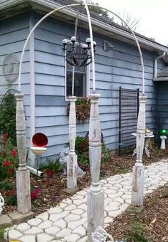 an outdoor garden area with white pillars and lights on the side of a blue house