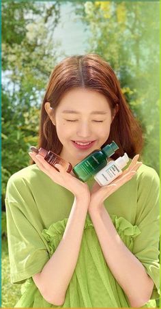 a woman holding two bottles of skin care products in front of her face and smiling