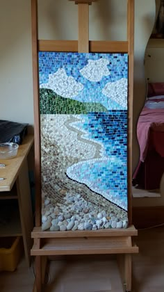 an easel with a mosaic on it in front of a bed