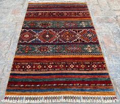 a multicolored rug with fringes on the ground