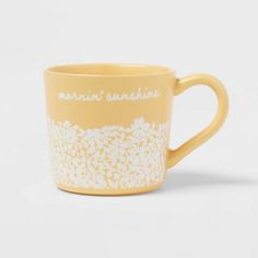 a yellow coffee cup with white lace on the bottom and words written in white ink