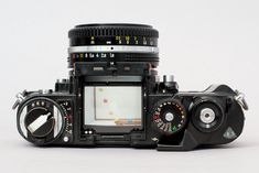 an old fashioned camera sitting on top of a white surface with the lens facing up