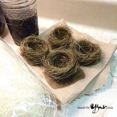 three birds nests sitting on top of a napkin next to a jar