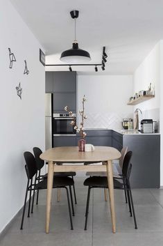 a dining table and chairs in a small room with an open kitchen area on the other side