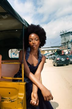 a woman sitting in the back of a yellow truck with an afro on her head