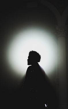 the silhouette of a person standing in front of a light