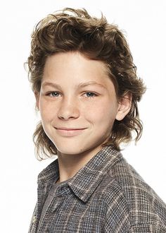 a young boy with curly hair smiling at the camera