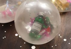 a bottle in a glass ball with confetti on the table next to it