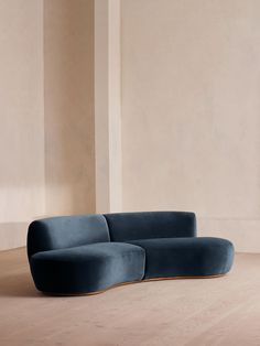 a blue couch sitting on top of a hard wood floor next to a white wall