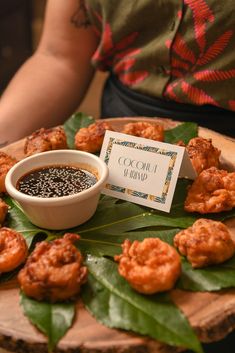 a plate with some food on it next to a bowl of black sesame seeds and a sign that says coconut shrimp