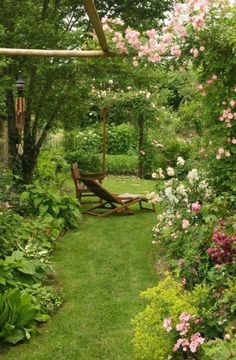 a wooden bench sitting in the middle of a lush green park filled with pink flowers