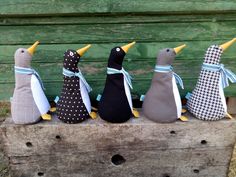 five stuffed penguins are lined up on a wooden box with ribbons tied around their necks