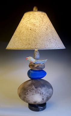 a lamp that is sitting on top of some rocks with a bird perched on it