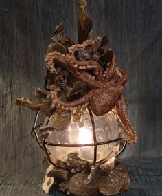 an octopus is sitting in a glass vase with shells and other things around it on a table