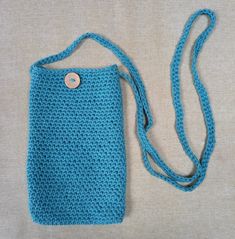 a crocheted blue bag with a button on it's side and a cord attached to the back