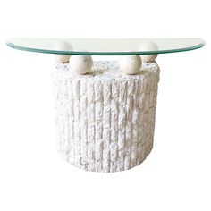 a glass table with two balls on top and a white base in the shape of a log