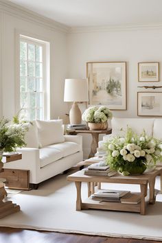 a living room with white furniture and flowers on the coffee table in front of it