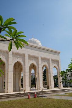 a large white building with arches on the front and side walls, surrounded by trees