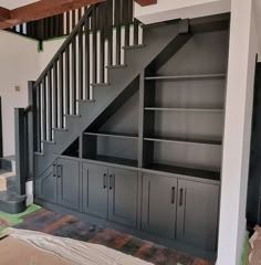 an empty room with cabinets under the stairs