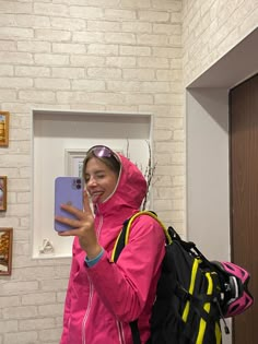 a woman taking a selfie with her cell phone in front of a brick wall