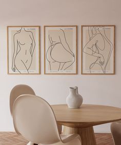 three framed nude drawings hang on the wall next to a dining room table and chairs