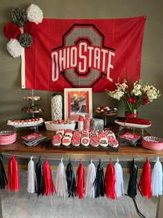 the dessert table is decorated with red, white and black tassels on it