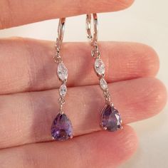 Theses Beautiful Purple Water Drop Hoop Pierced Earrings Are Made Of 18k White Gold Filled With (Lab Created) Purple And White Topaz Zircon Stones. Brand New, Never Been Worn. These Fine Quality Earrings Are Perfect For Everyday Wear Or A Special Gift. Get An $18 Gift Of Your Choice In My Listings W/Purchase Of Two Or More Items. Please Send Offers And Questions. Earrings: 37x6mm Or 1.47 X .24" Large Pear Shape Stone: 6x8mm Or .34" X .31" Hoop Diameter: 11mm Or .43" Silver Teardrop Earrings With Prong Setting As Gift, Silver Crystal Earrings With Lever Back For Anniversary, Light Purple Earrings, Purple Reception, Purple Drop Earrings, Sliver Earrings, Purple Water, Formal Earrings, Zircon Earrings