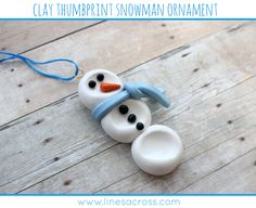 two snowmen made out of clay sitting on top of a wooden floor next to a blue string