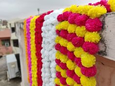 colorful garland hanging from the side of a wooden structure with white and yellow flowers on it