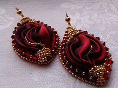 pair of red and gold earrings on white cloth