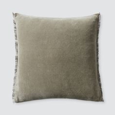 a grey pillow with fringe trim